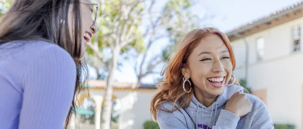 two students sitting outside smiling