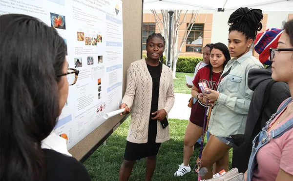 A student giving a presentation in front of a group outside.