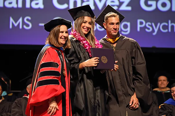 President Ann and professor smiling with a graduate