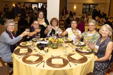 alumnae sitting at a table smiling and holding up glasses to cheers