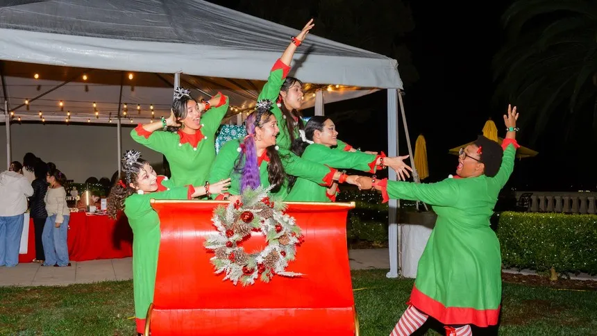 Members of The Muses bring holiday cheer as they pose playfully with the sleigh during Lighting of the Circle.
