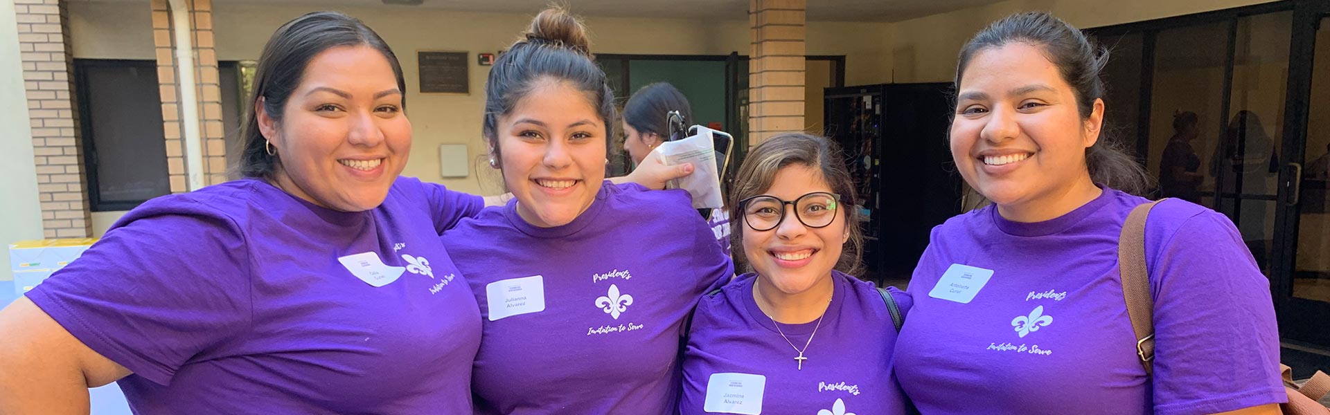 Four students smiling at the camera with their arms around each other.