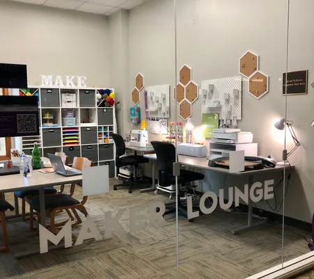 Room filled with crafting supplies and equipment, the words Maker Lounge appear on the windows