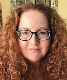 a portrait of a woman with curly red hair and glasses