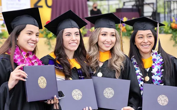 Four students smiling at graduation