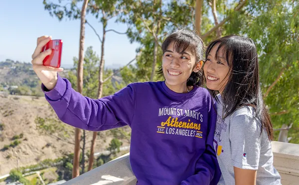 Two students taking a selfie outside