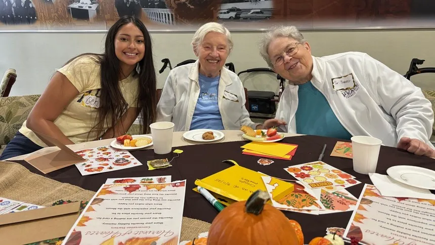 Genesis Gonzalez, a member of Kappa Delta Chi, shares a moment of laughter and fall-themed activities with Sisters Joan Hagen (center) and Therese Denham, CSJs (right).