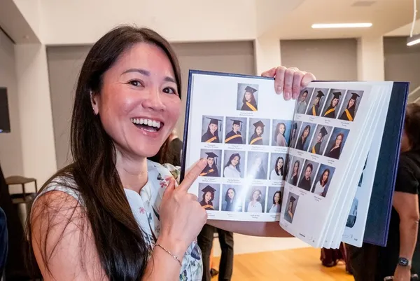 Mount alum smiling and pointing at yearbook