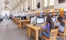 Students sitting at computer desks in a large library hall.