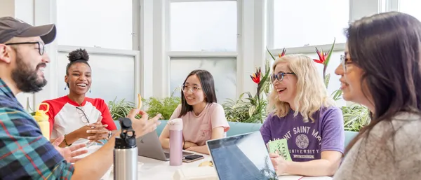group of students talking and working at a table.