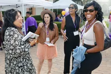 four alums laughing and talking outside at a campus event