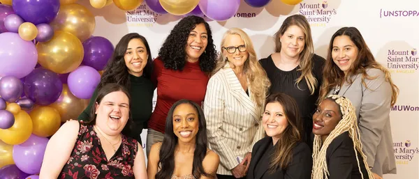 Group of alums smiling in group photo in front of balloon arch and MSMU backdrop