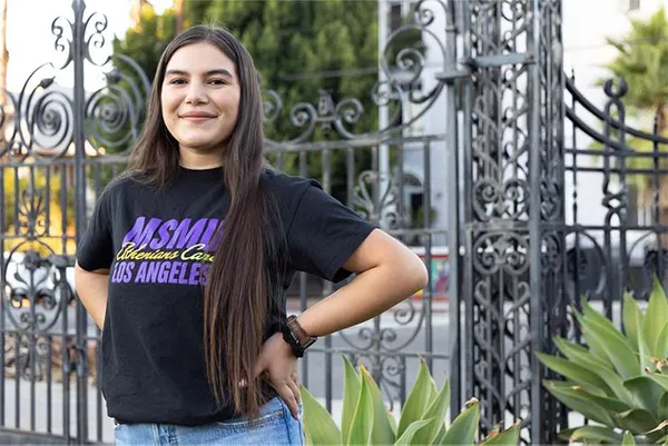 Female student smiling at front entrance to campus with an MSMU shirt on.