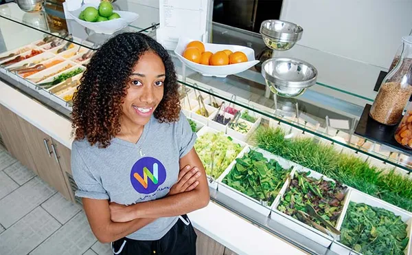 student smiling standing next to salad station