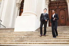 two government workers talking while walking down the steps of a government building