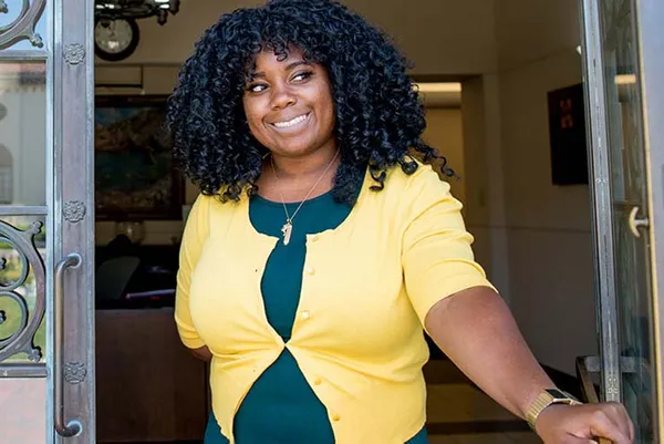 female student smiling opening the door