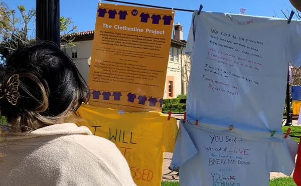 female student reading shirts pinned to a clothesline