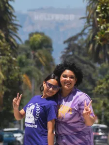 Two students posing with the Hollywood sign in the background