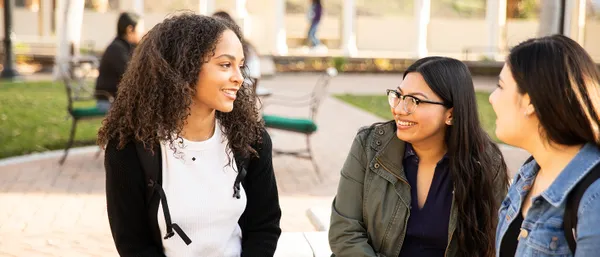 Three students sitting outside talking