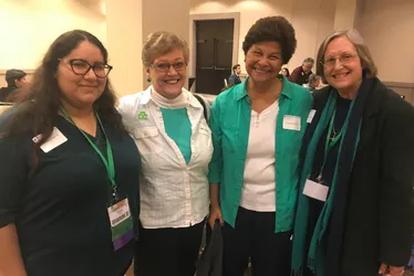 Women shoulder to shoulder smiling at a conference