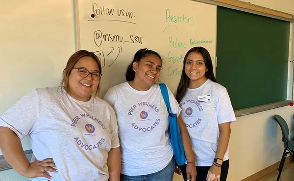 wellness students smiling in front of a classroom