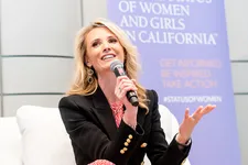 A woman speaking into a microphone while sitting on stage