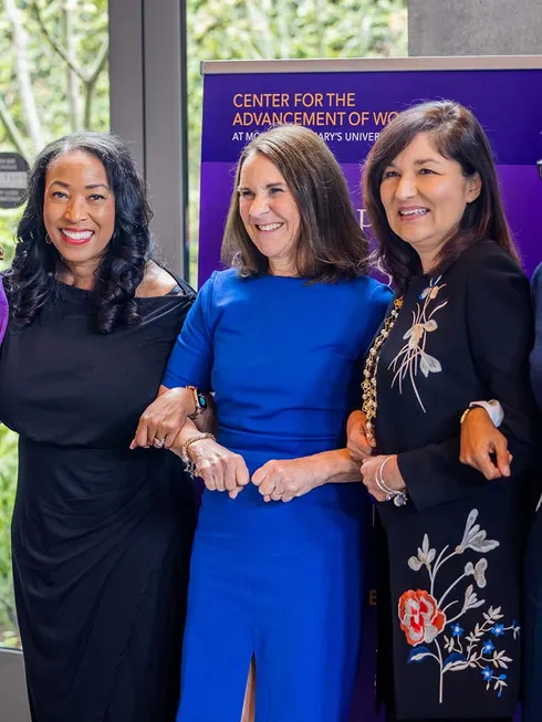three women linking arms at event smiling