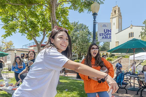 students smiling playing cornhole
