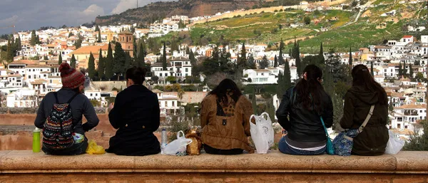 Five students sitting on a wall overlooking a town