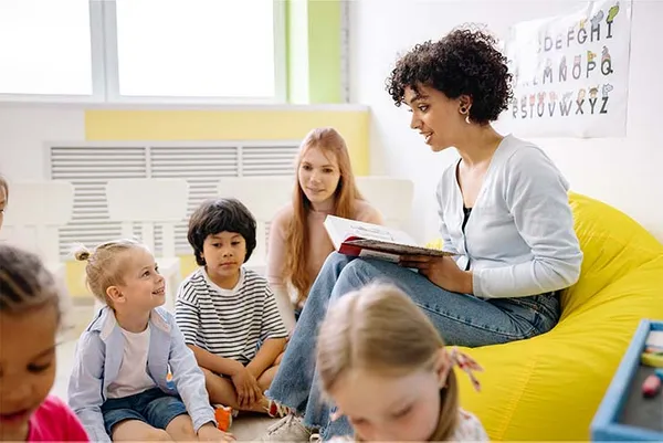 young teacher reading a book to a group of kids