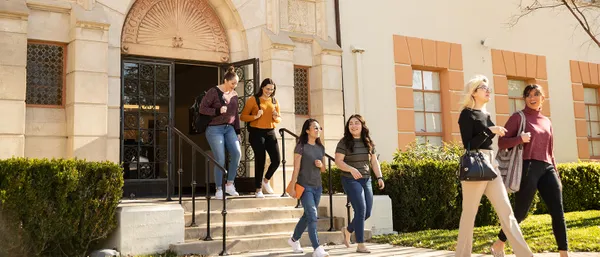 students walking out of campus building chatting