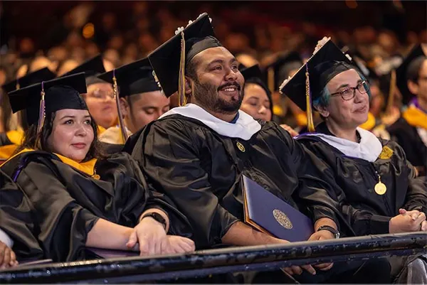 graduting students smiling holding their degrees