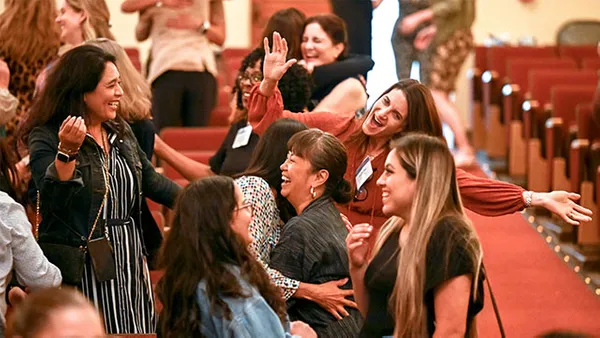women in crowd smiling and hugging each other
